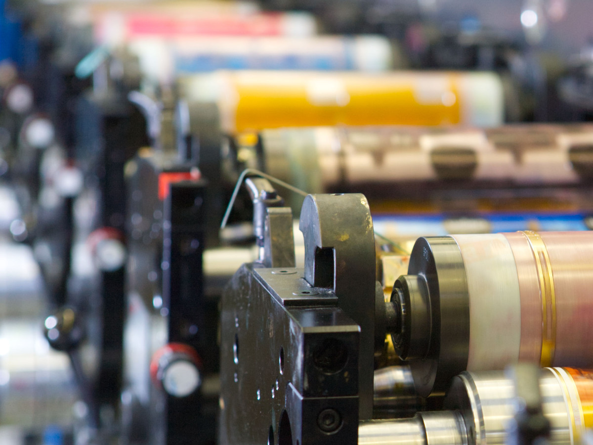 Trükimasin tööhoos – vaade trükivõllidele, mis sümboliseerib täpsust ja kvaliteetset trükkimist.